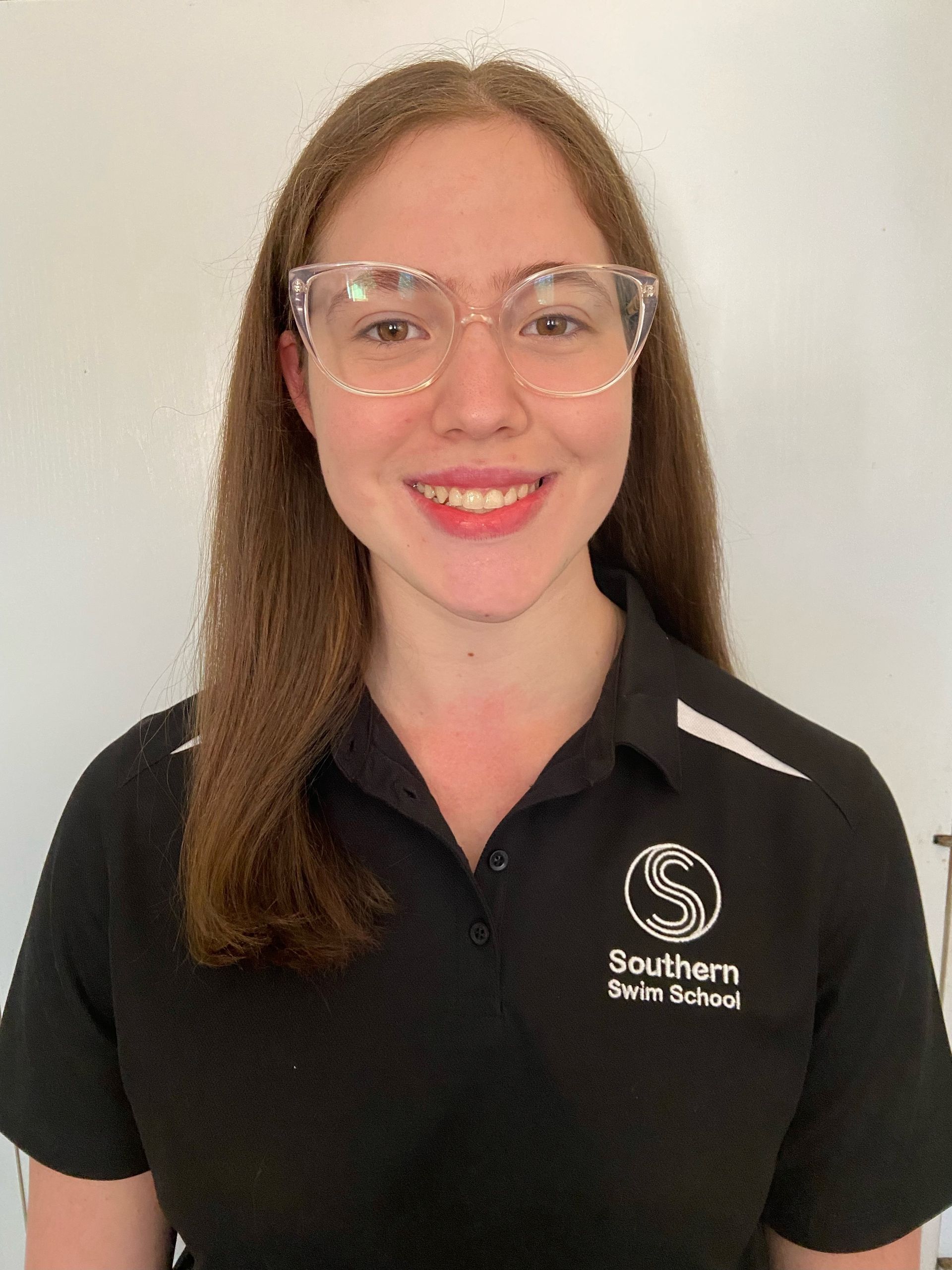 A woman wearing glasses and a black shirt is smiling for the camera.