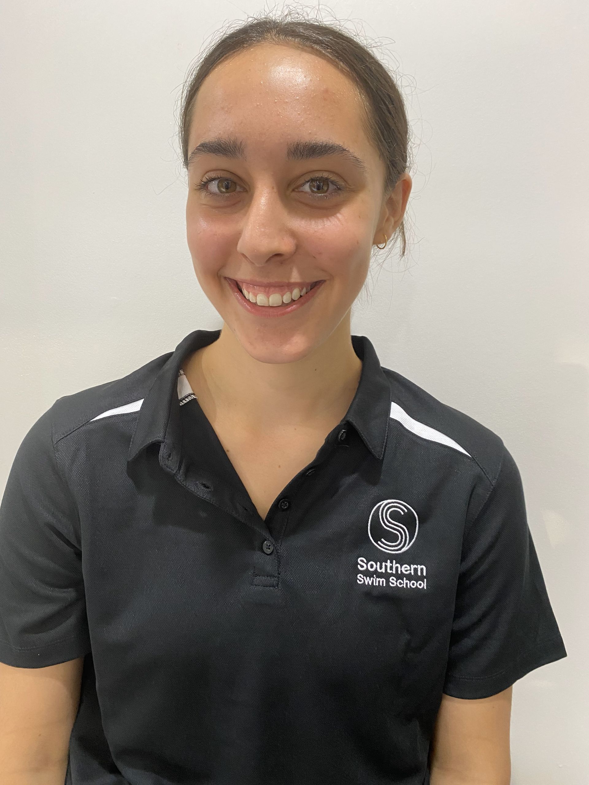 A woman wearing a black polo shirt is smiling for the camera.