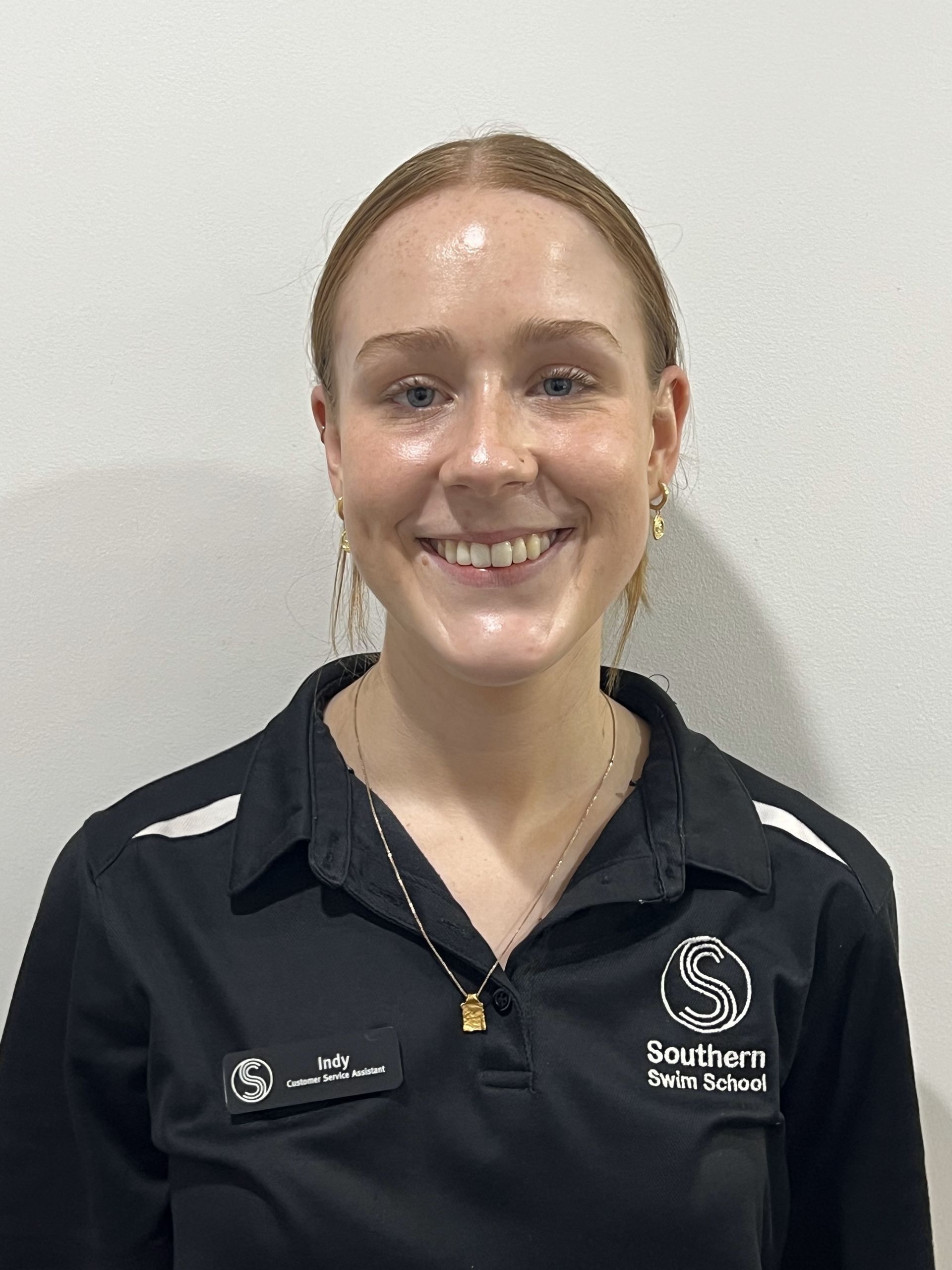 A woman wearing a black shirt and a necklace is smiling for the camera.