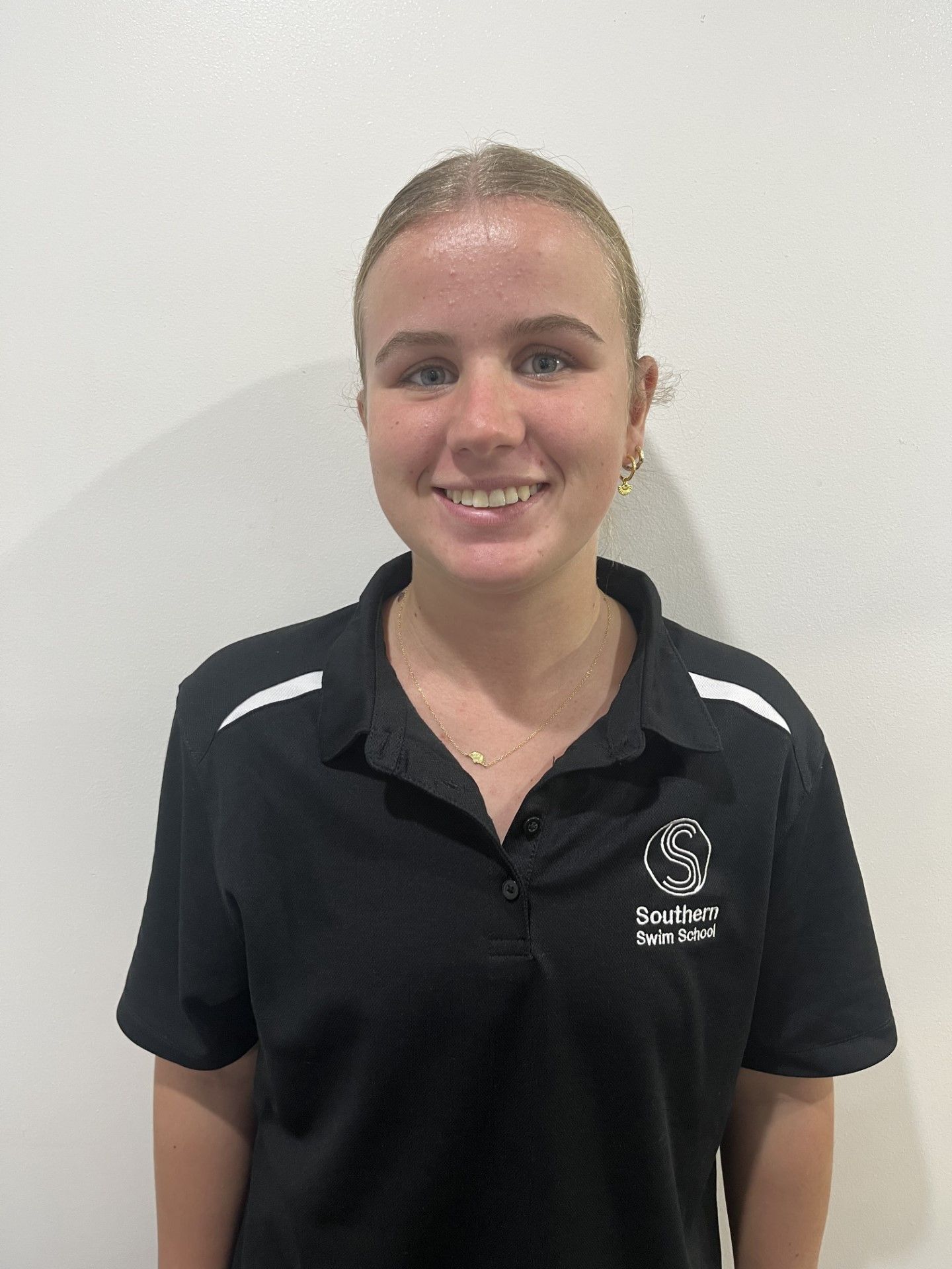 A young woman wearing a black polo shirt is smiling for the camera.