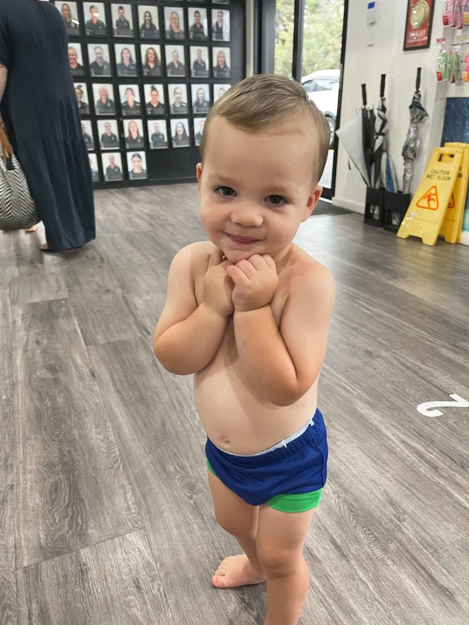 A little boy without a shirt is standing in a room.