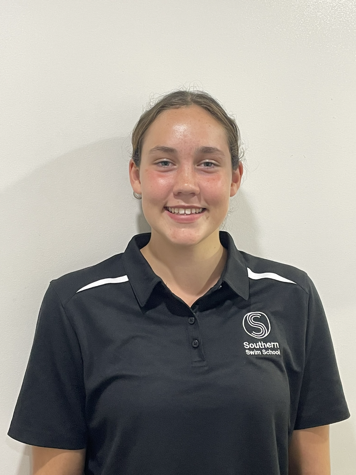 A young woman wearing a black polo shirt is smiling for the camera.