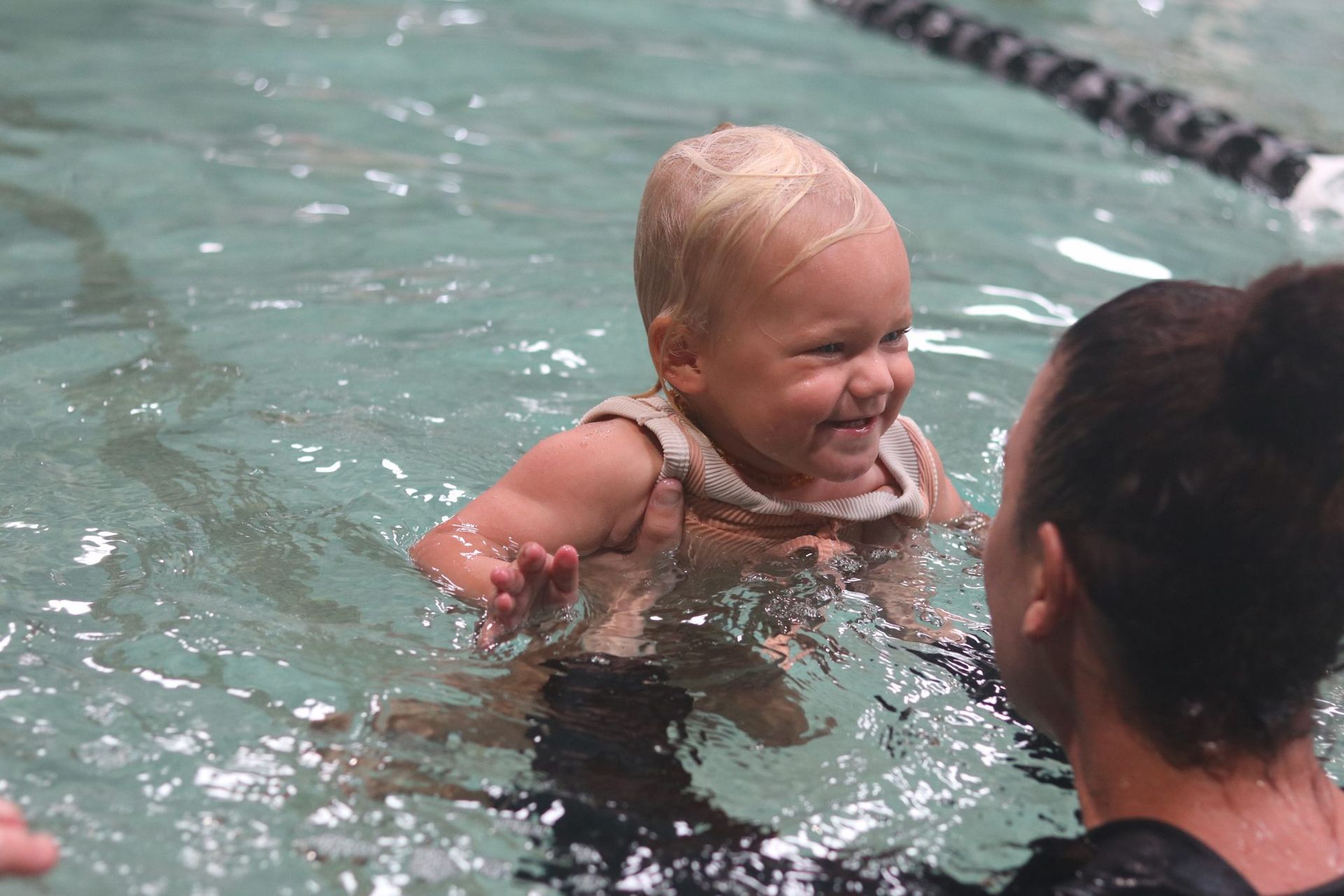 A woman is teaching a baby how to swim in a swimming pool.