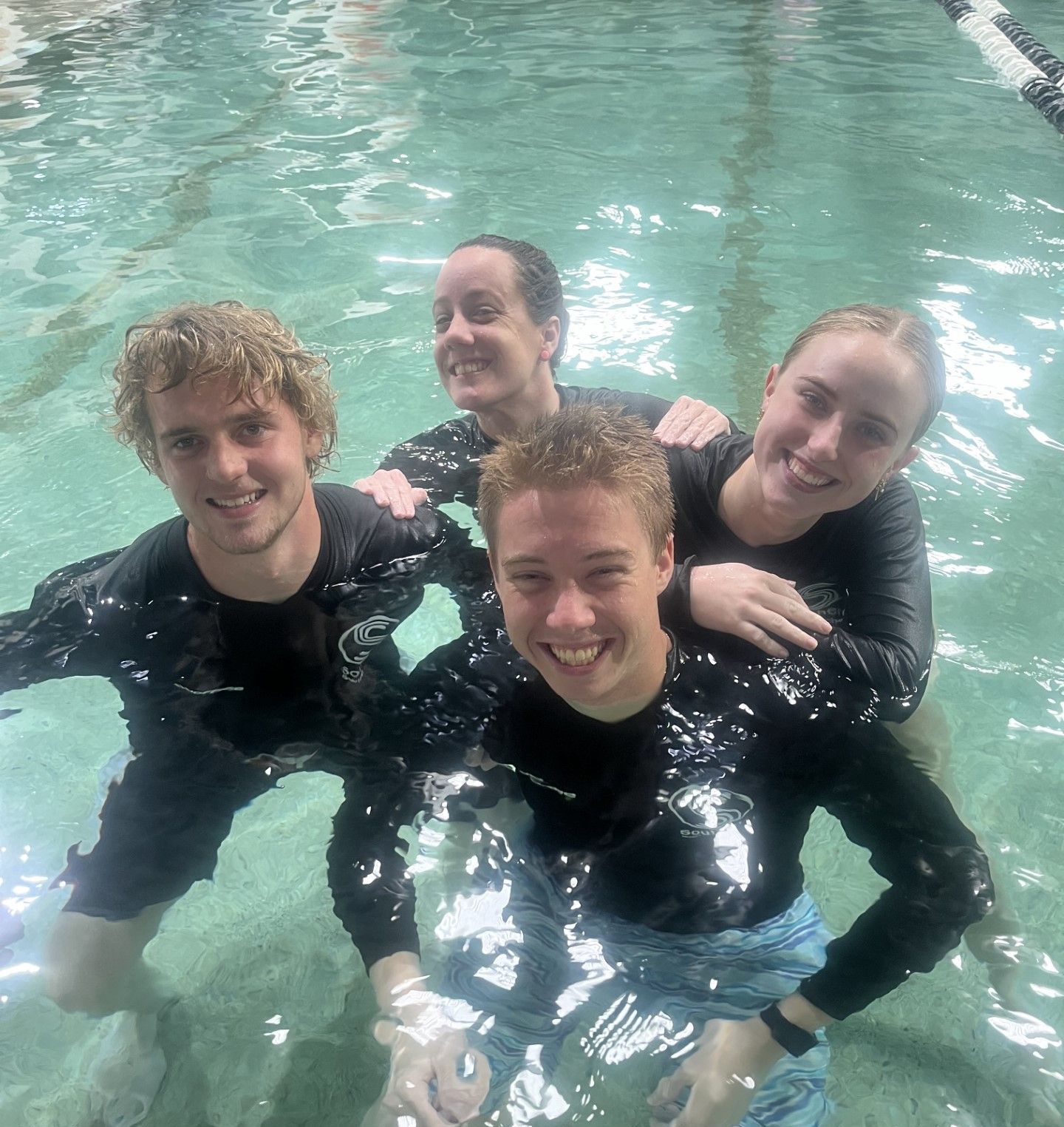 A group of people are posing for a picture in a swimming pool