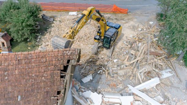 An aerial view of a bulldozer demolishing a house.