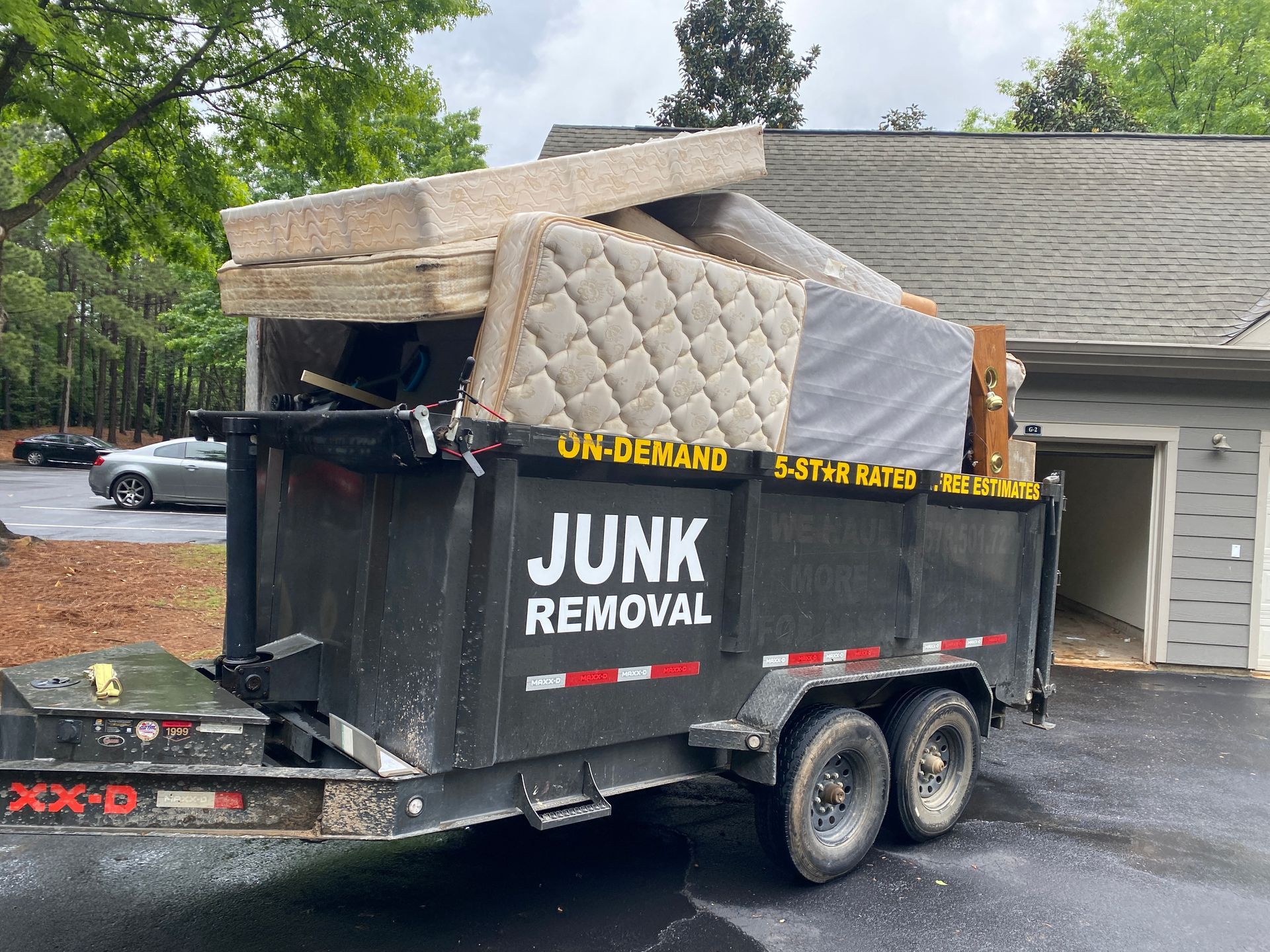A dumpster filled with junk is parked in front of a house.