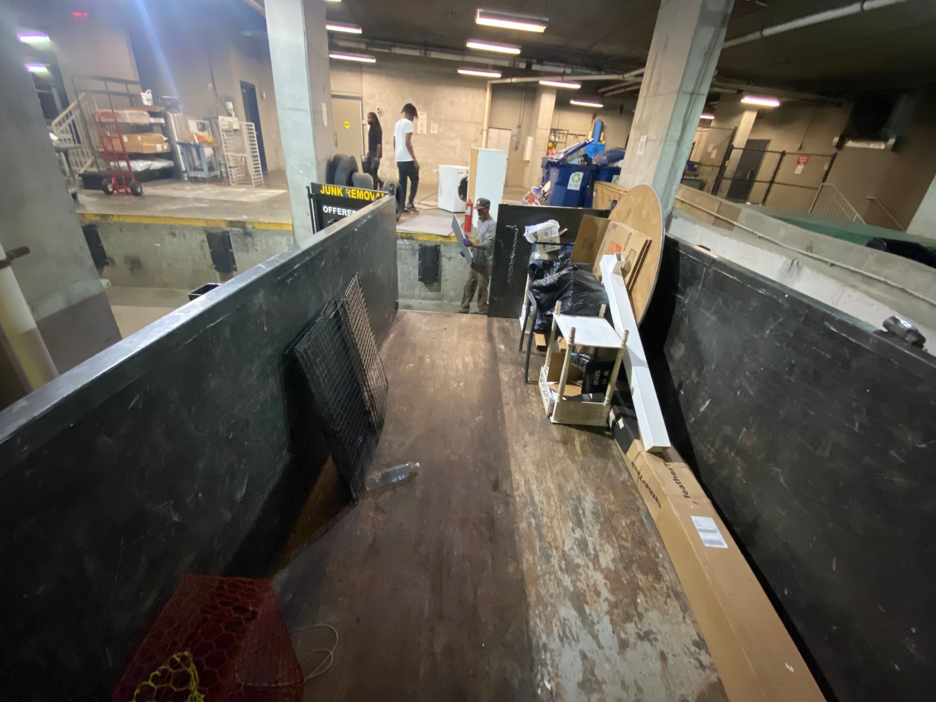 A warehouse with a lot of boxes on the floor and people standing in the background.