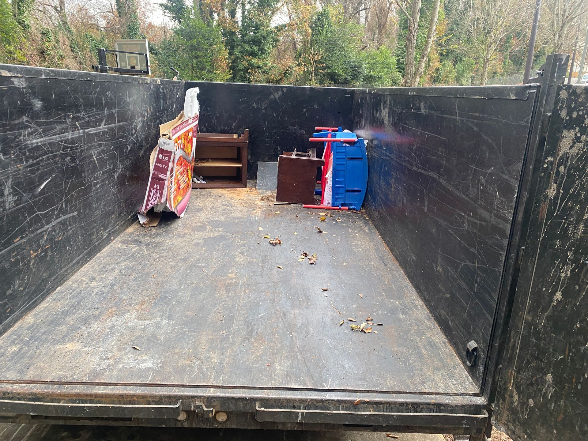 A dumpster filled with a lot of junk and a blue chair.