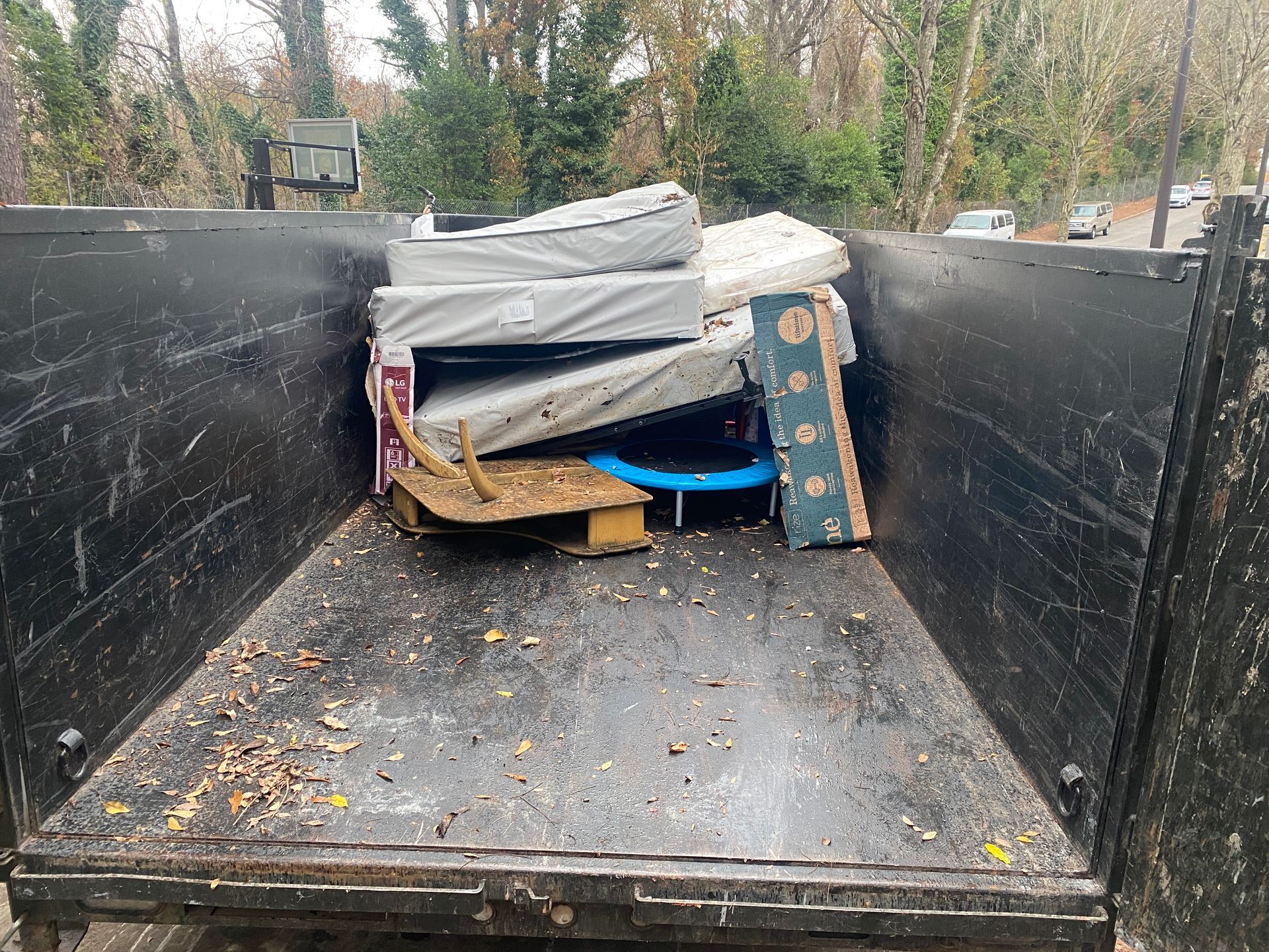 A dumpster filled with mattresses , boxes , and other items.