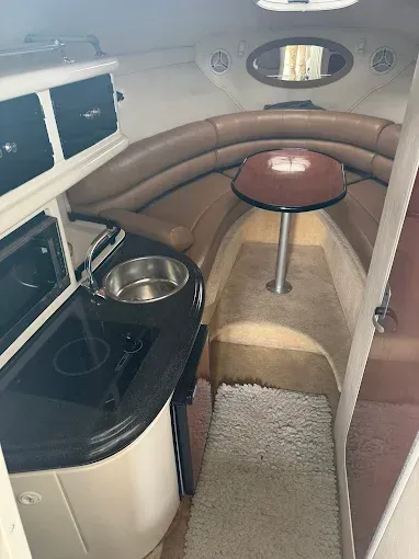 Interior boat galley with sink, stove, microwave, and seating around a table.