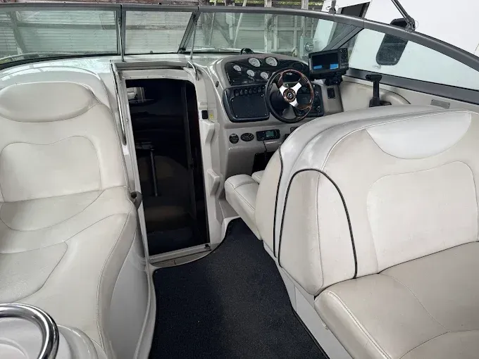 Interior of a white speedboat: helm, seats, black trim, and a small cabin.