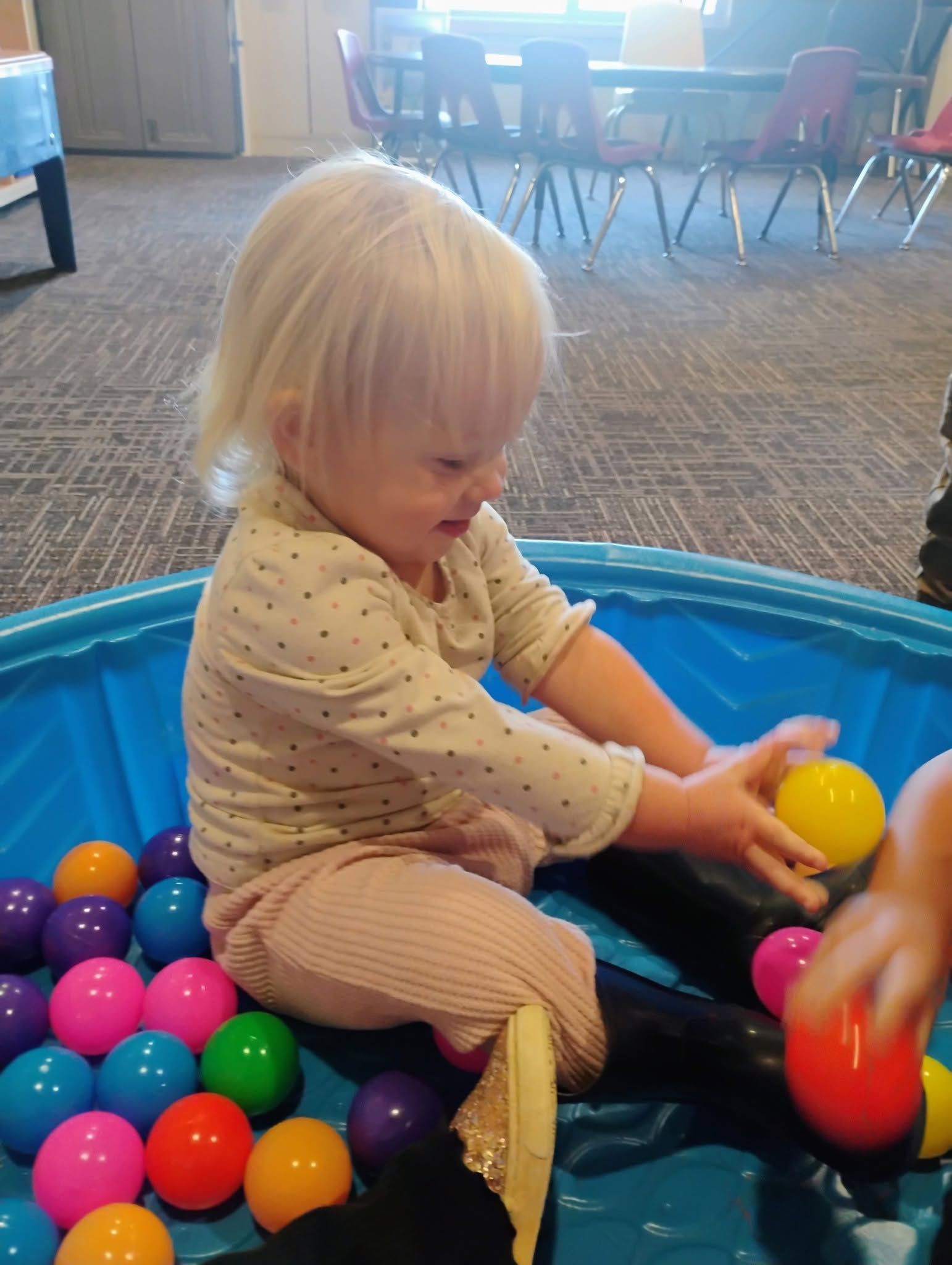 Two people smiling and giving a high-five at a small table with colorful toys in a bright playroom