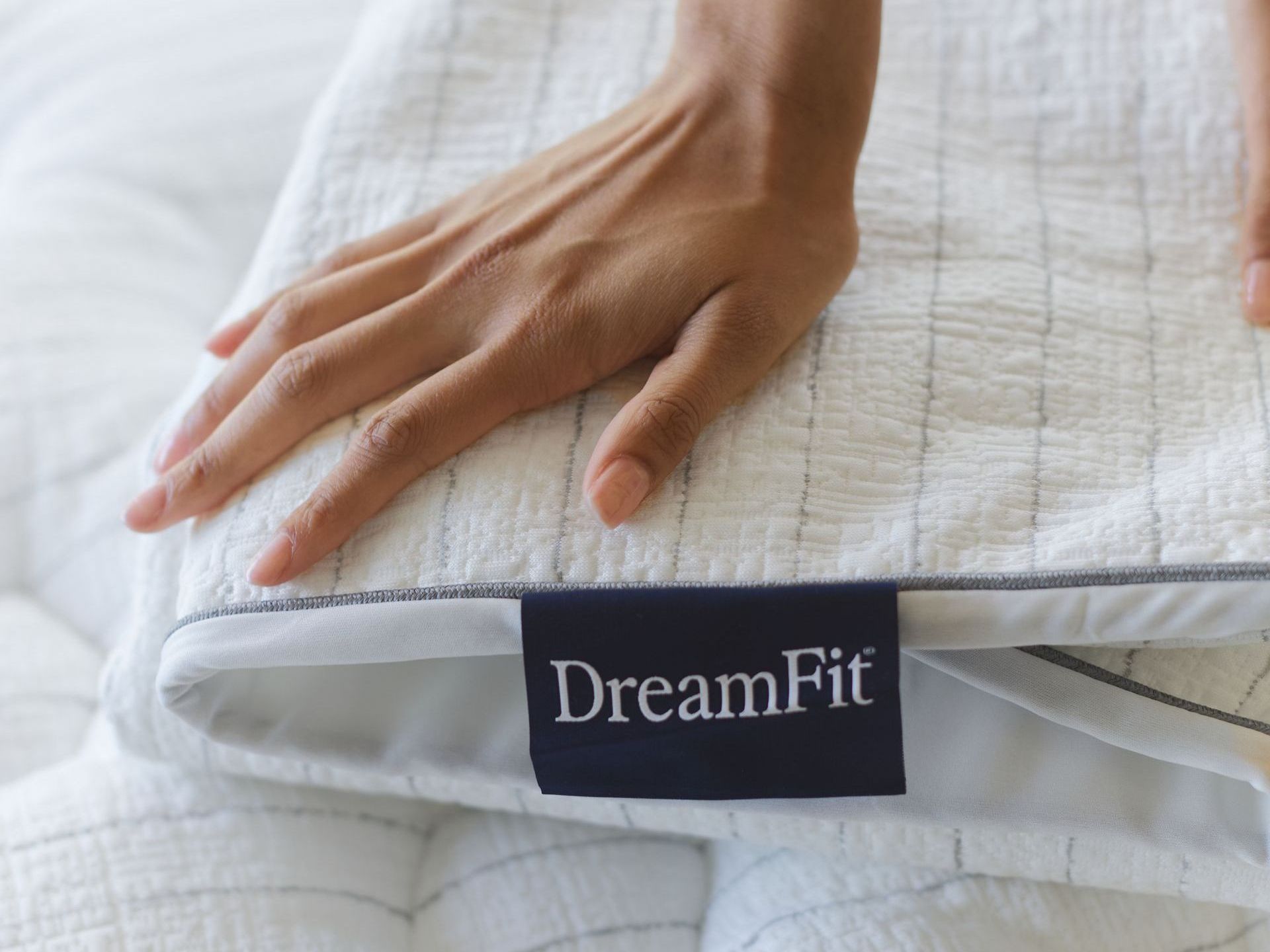 A person is putting a pillow on top of a bed.