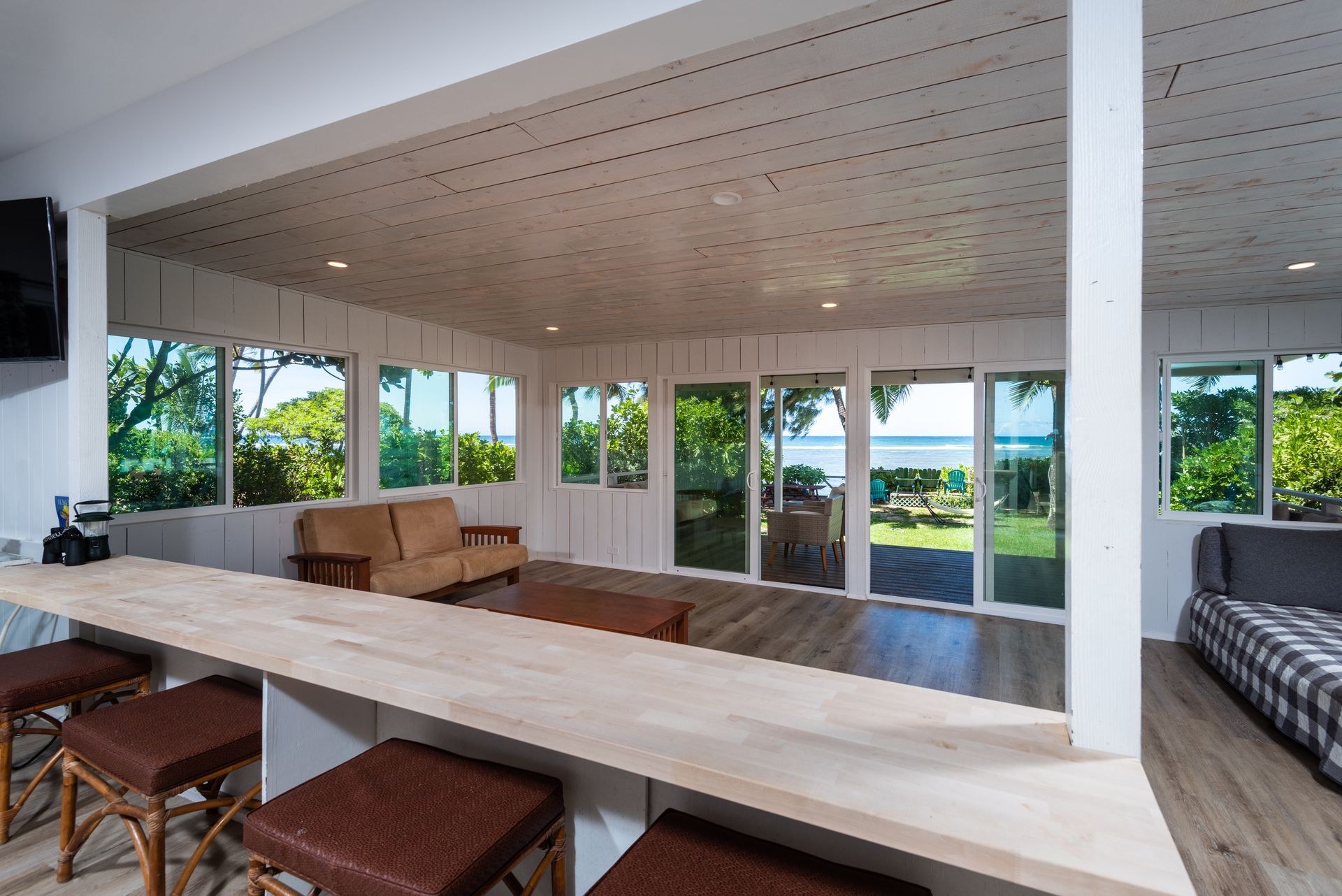 Interior space with bar, sofas, and large windows overlooking a waterfront view. Interior space with bar, sofas, and large windows overlooking a waterfront view.