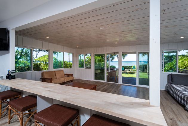 Interior space with bar, sofas, and large windows overlooking a waterfront view. Interior space with bar, sofas, and large windows overlooking a waterfront view.