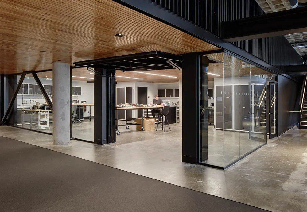 Modern office interior with glass walls, concrete floors, and wooden ceiling.