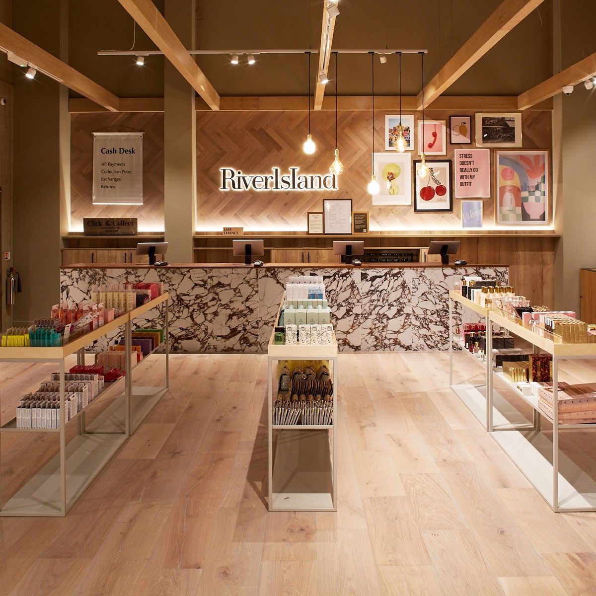 Interior of a River Island store with light wood floors, various displays, and a marble-patterned counter.