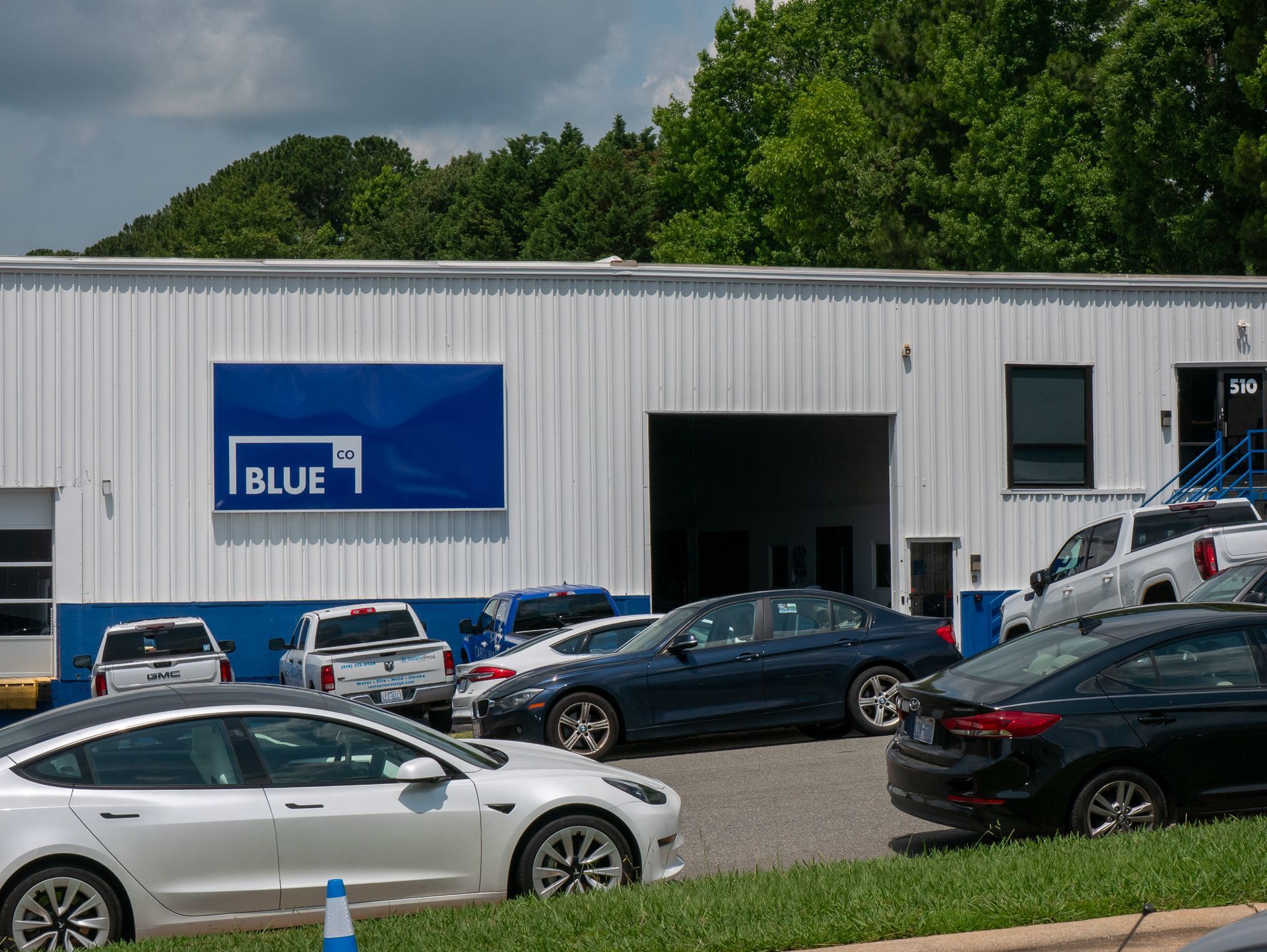 Outdoor patio with light gray couches, white pergola, blue-trimmed windows, and stone floor.