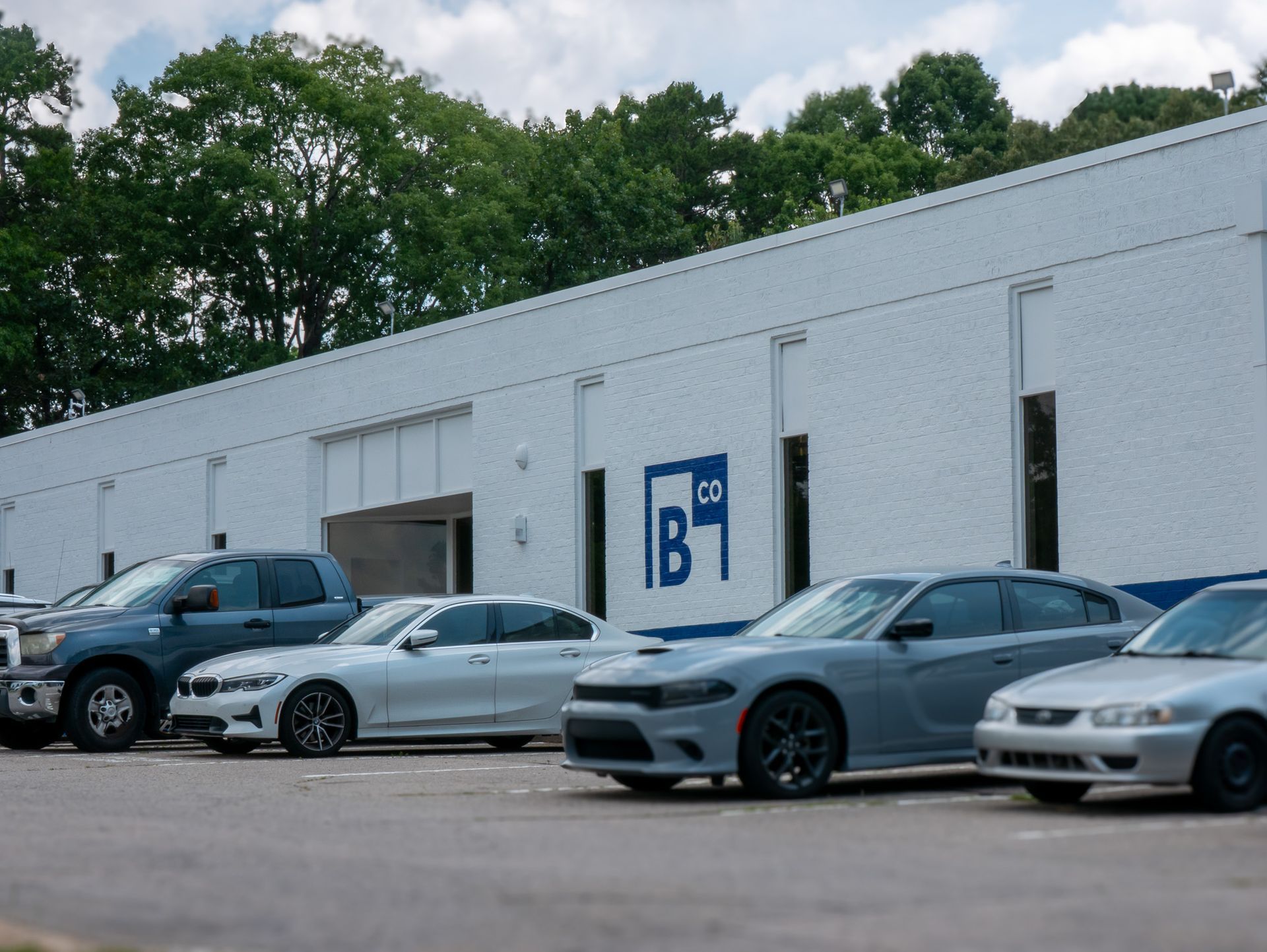 Outdoor patio with light gray couches, white pergola, blue-trimmed windows, and stone floor.