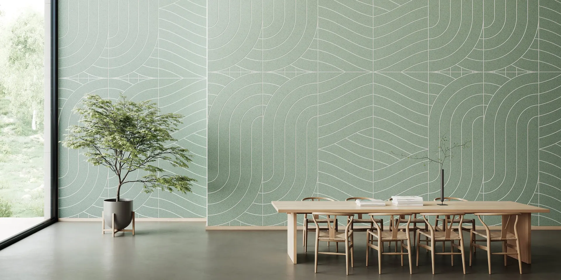 A minimalist interior with a tree in a pot, a large table with chairs, and a patterned green wall. Natural light floods the space.