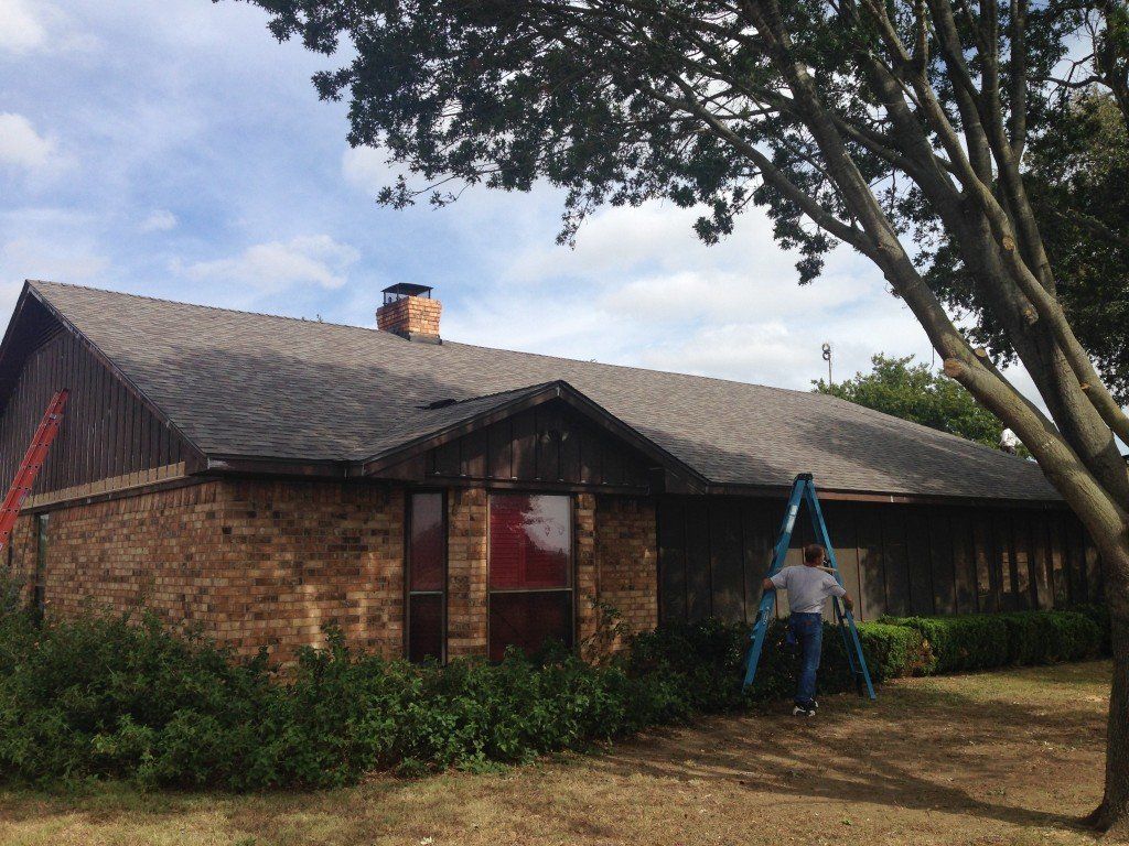 a man with a ladder stands in front of a brick house