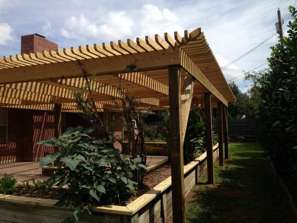 a wooden pergola with a brick chimney in the background