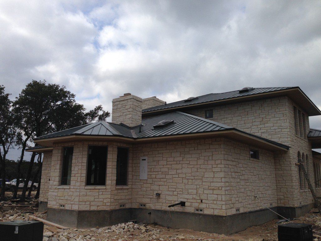 a white brick house with a metal roof