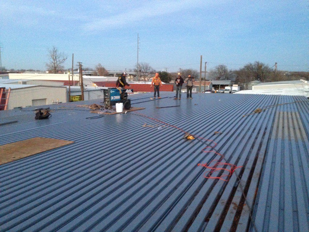 a group of men standing on top of a metal roof
