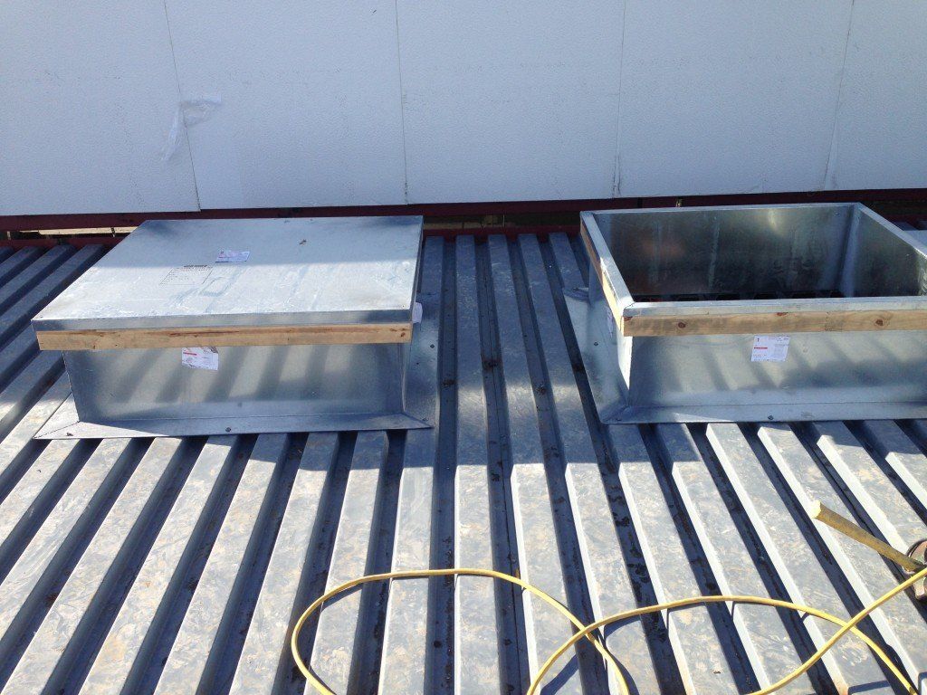 two square metal boxes on a metal roof