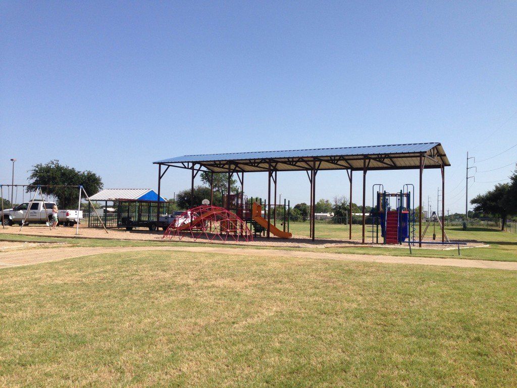 a playground with a covered area and a truck parked in the background