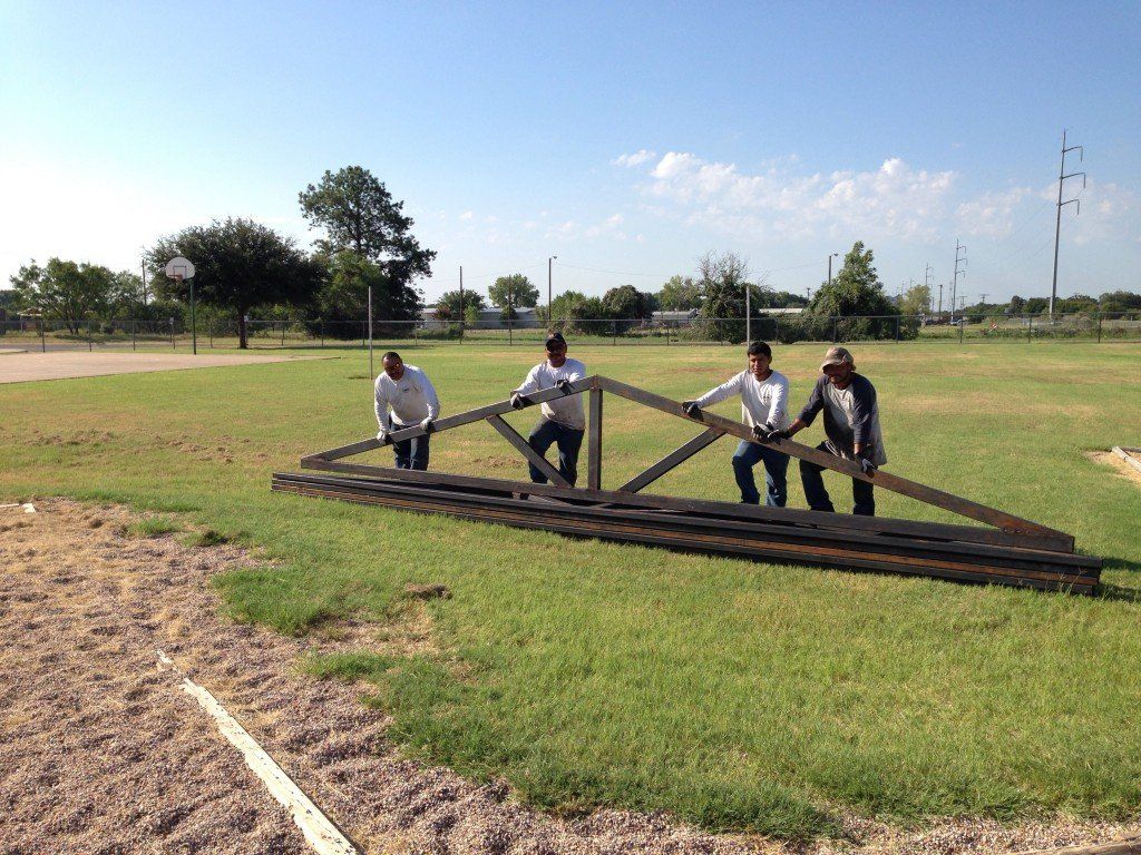 a group of men are carrying a large piece of wood in a field