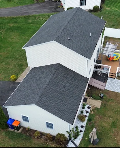 Overhead view of a two-story house with a detached garage. Both have dark grey shingle roofs.