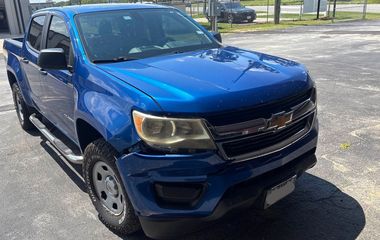 Blue Chevrolet Colorado pickup truck, damaged front, parked outdoors.