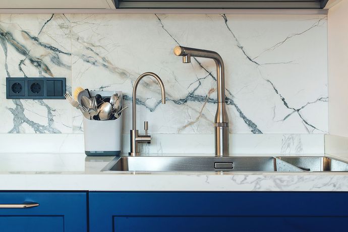 A kitchen sink with a stainless steel faucet and blue cabinets.