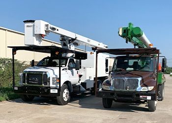 Two utility trucks are parked next to each other in a parking lot.