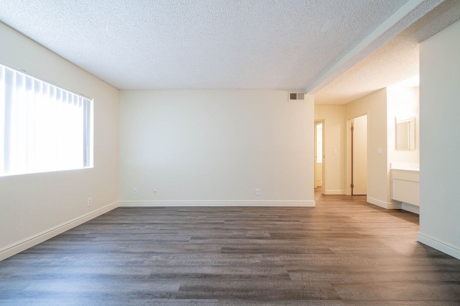 An empty living room with hardwood floors and white walls.