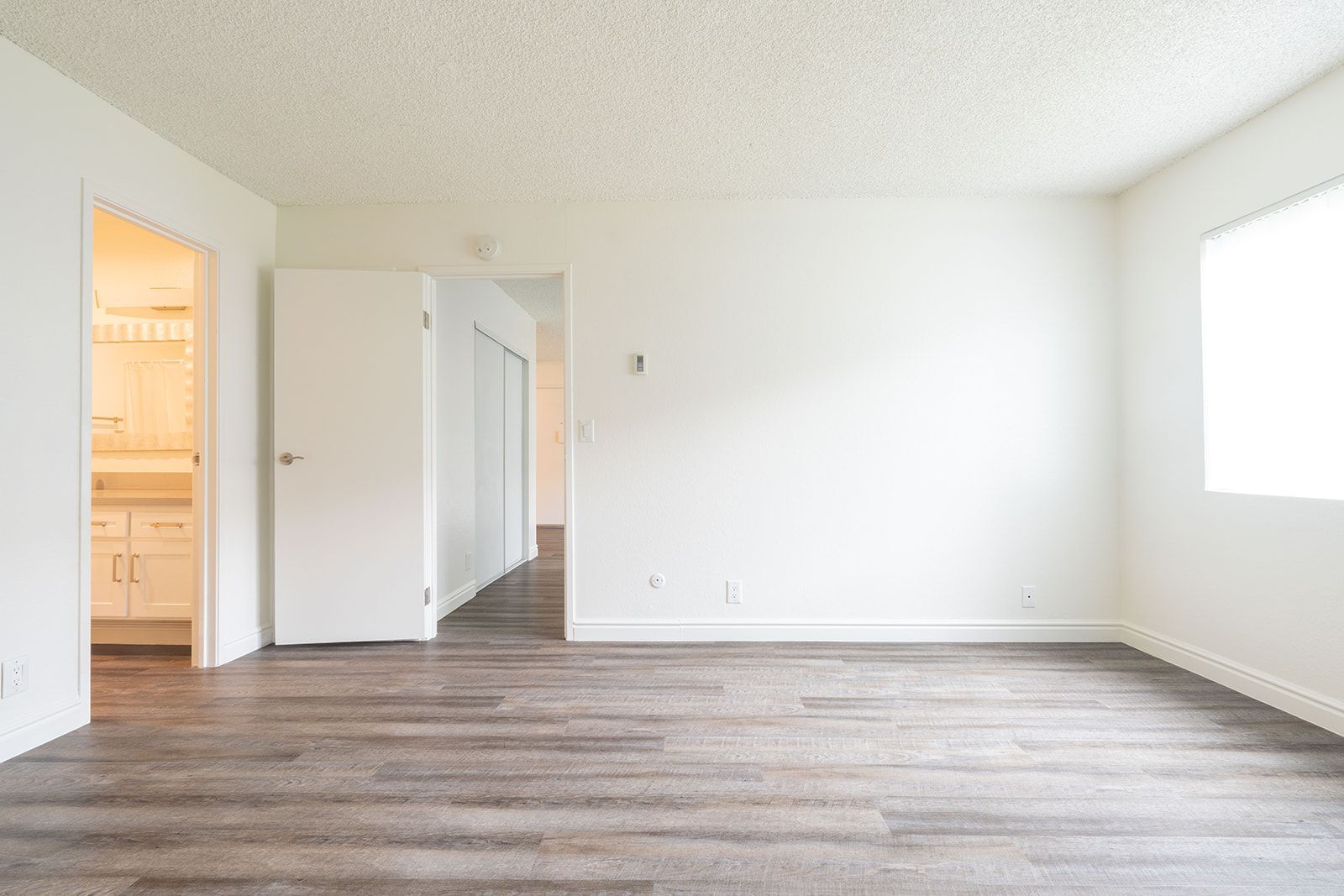 An empty living room with hardwood floors and white walls.
