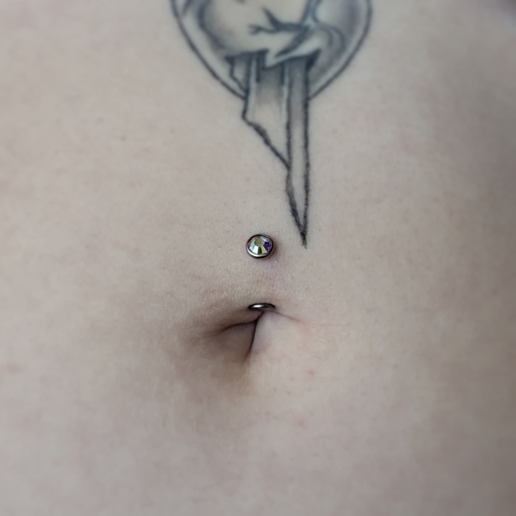 A person wearing pink gloves is piercing a woman 's belly button.