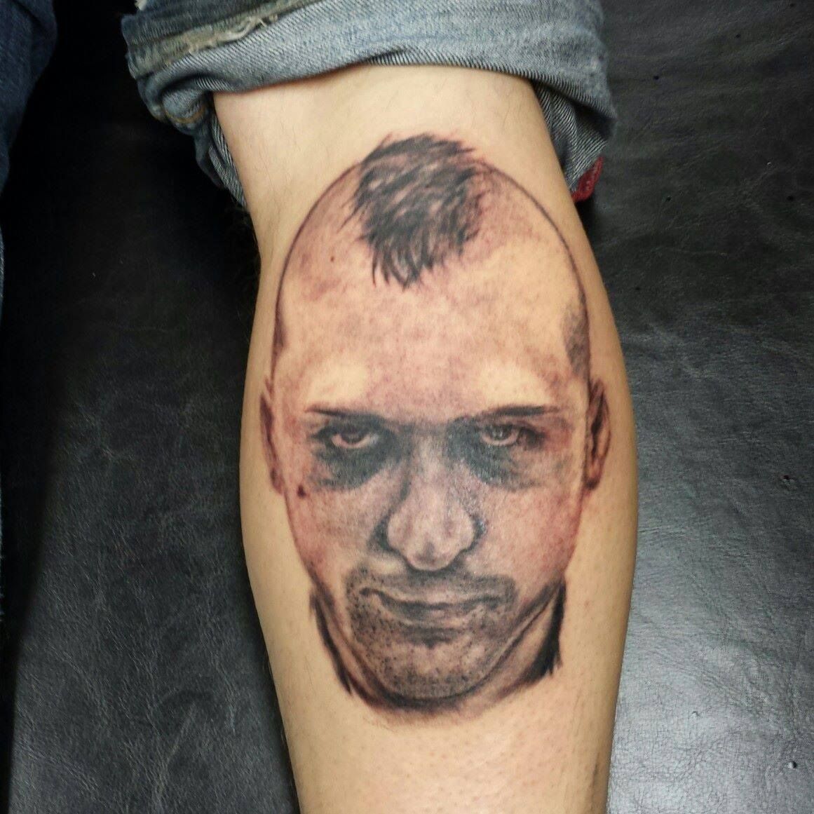 A person has a tattoo of a man 's face on their leg