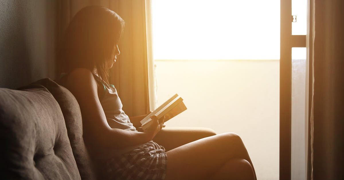 A woman is sitting on a couch reading a book.