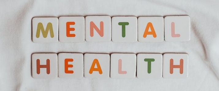 The word mental health is written in colorful tiles on a white surface.