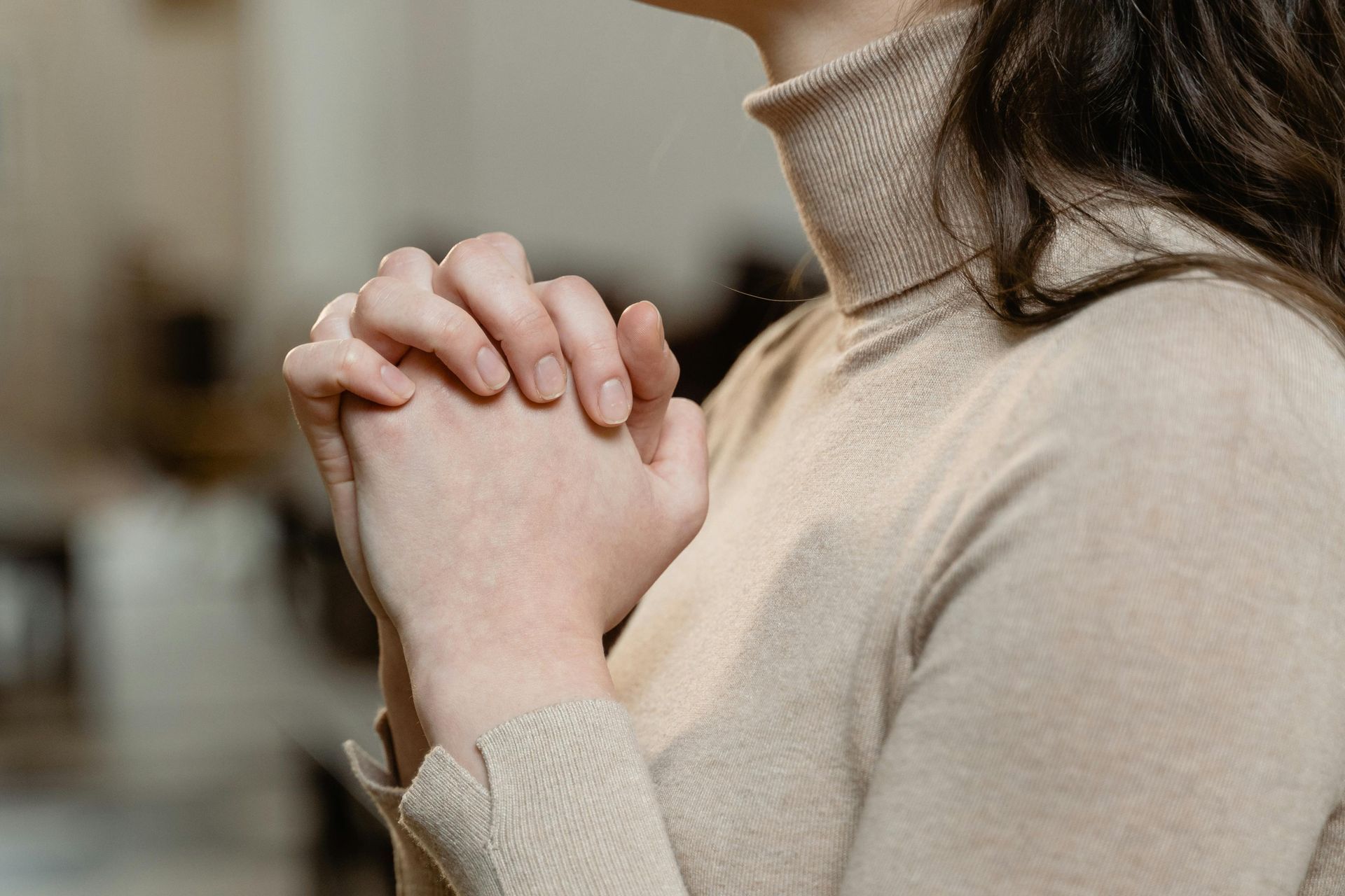 A woman is praying with her hands folded in prayer.