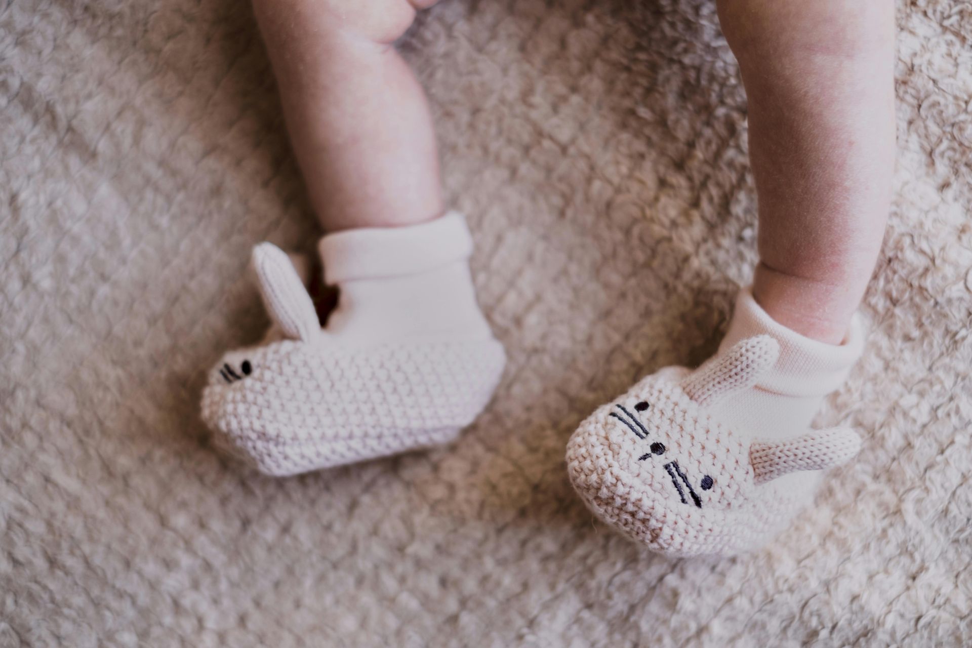 A pair of baby shoes are sitting on a bed.