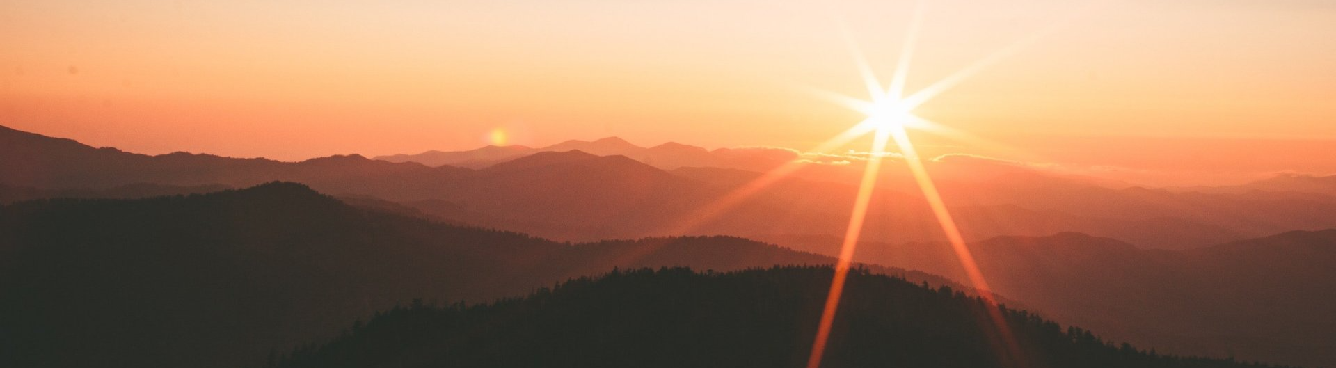 O sol brilha intensamente sobre as montanhas ao pôr do sol.
