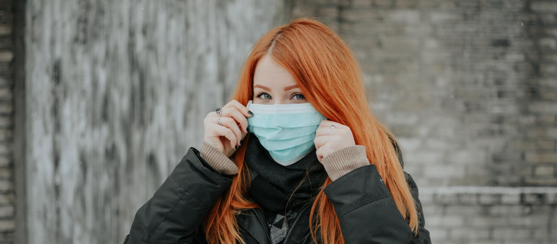 Uma mulher ruiva está usando uma máscara facial.