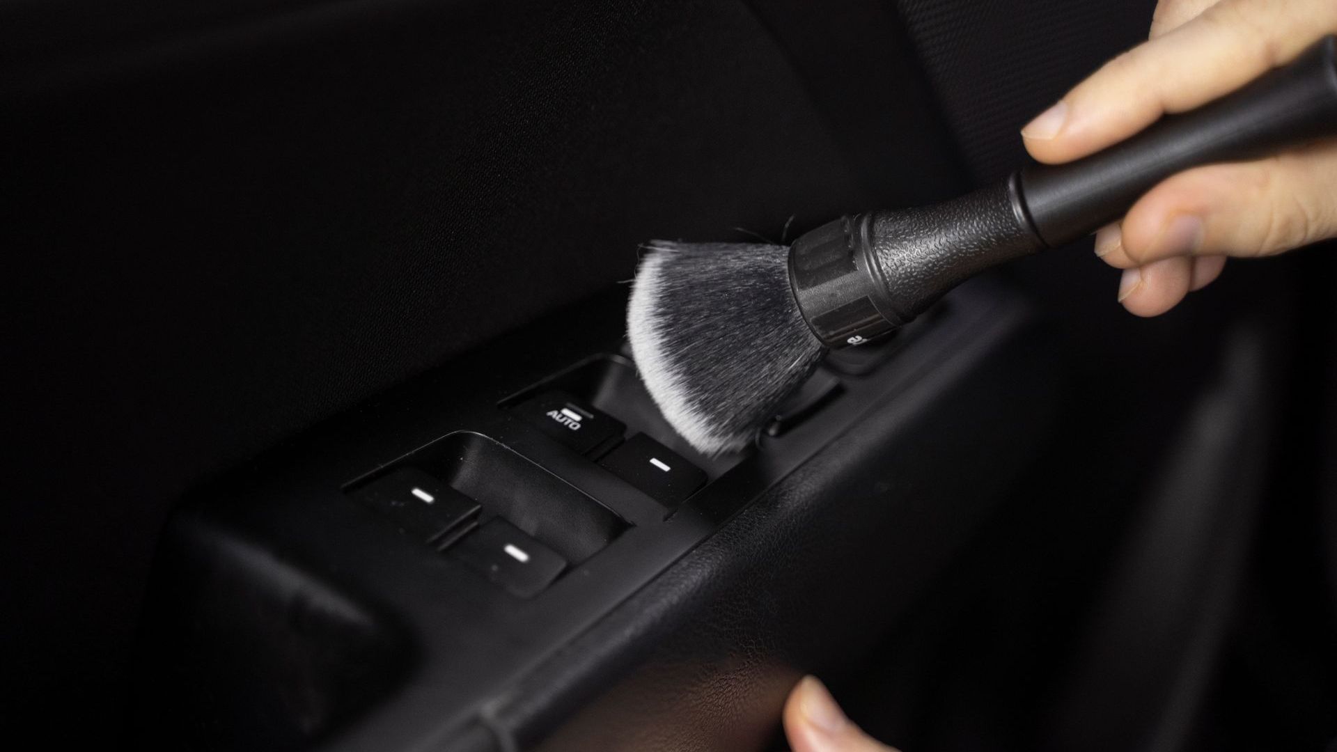 A person is cleaning a car door with a brush.
