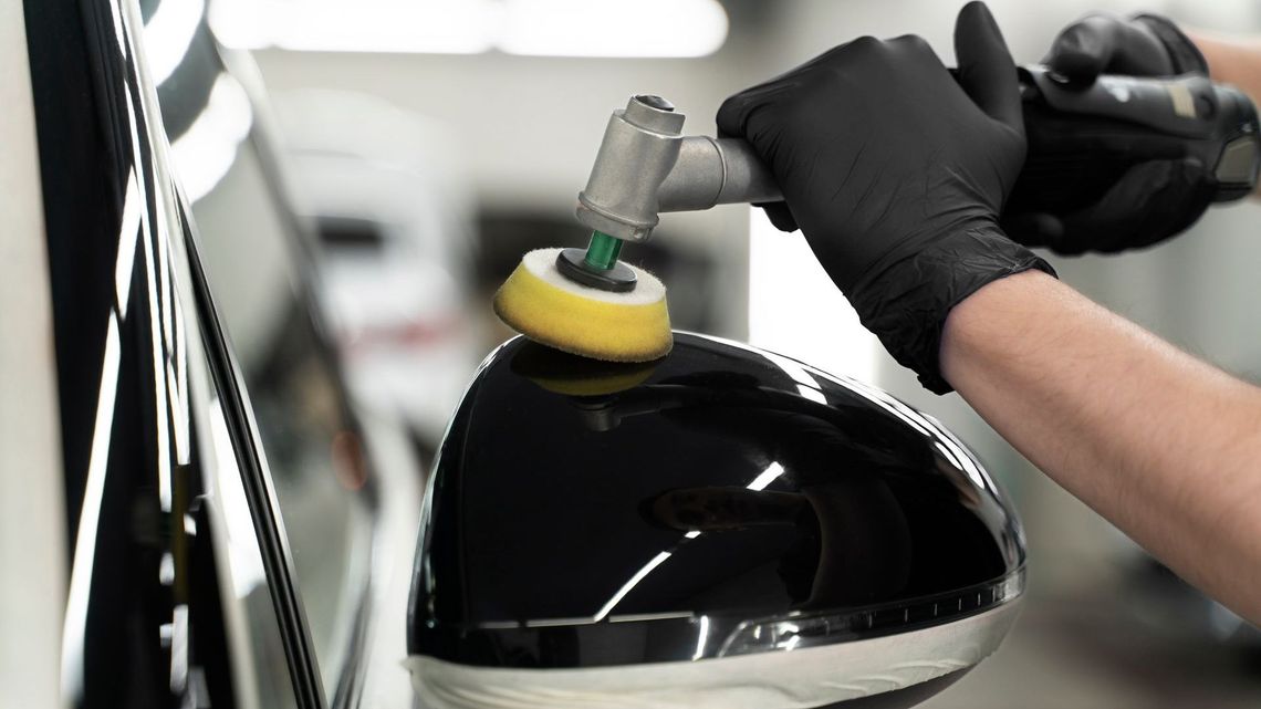 A person is cleaning the steering wheel of a car with a brush.