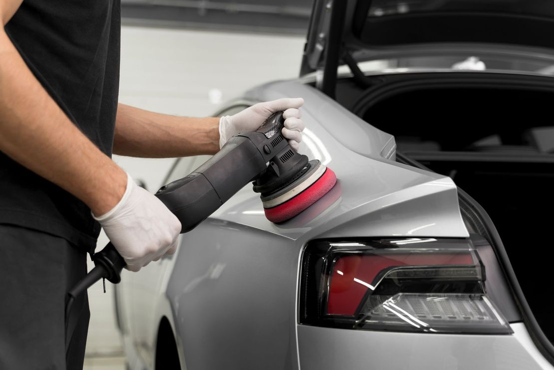 A man is polishing a car with a machine.