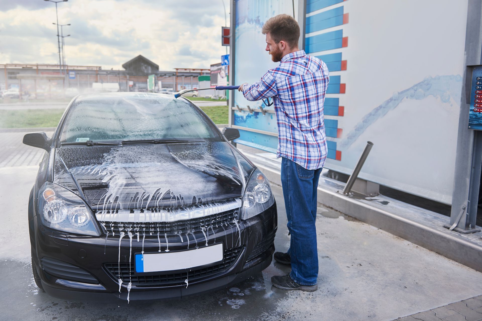 A man is washing his car at a car wash.