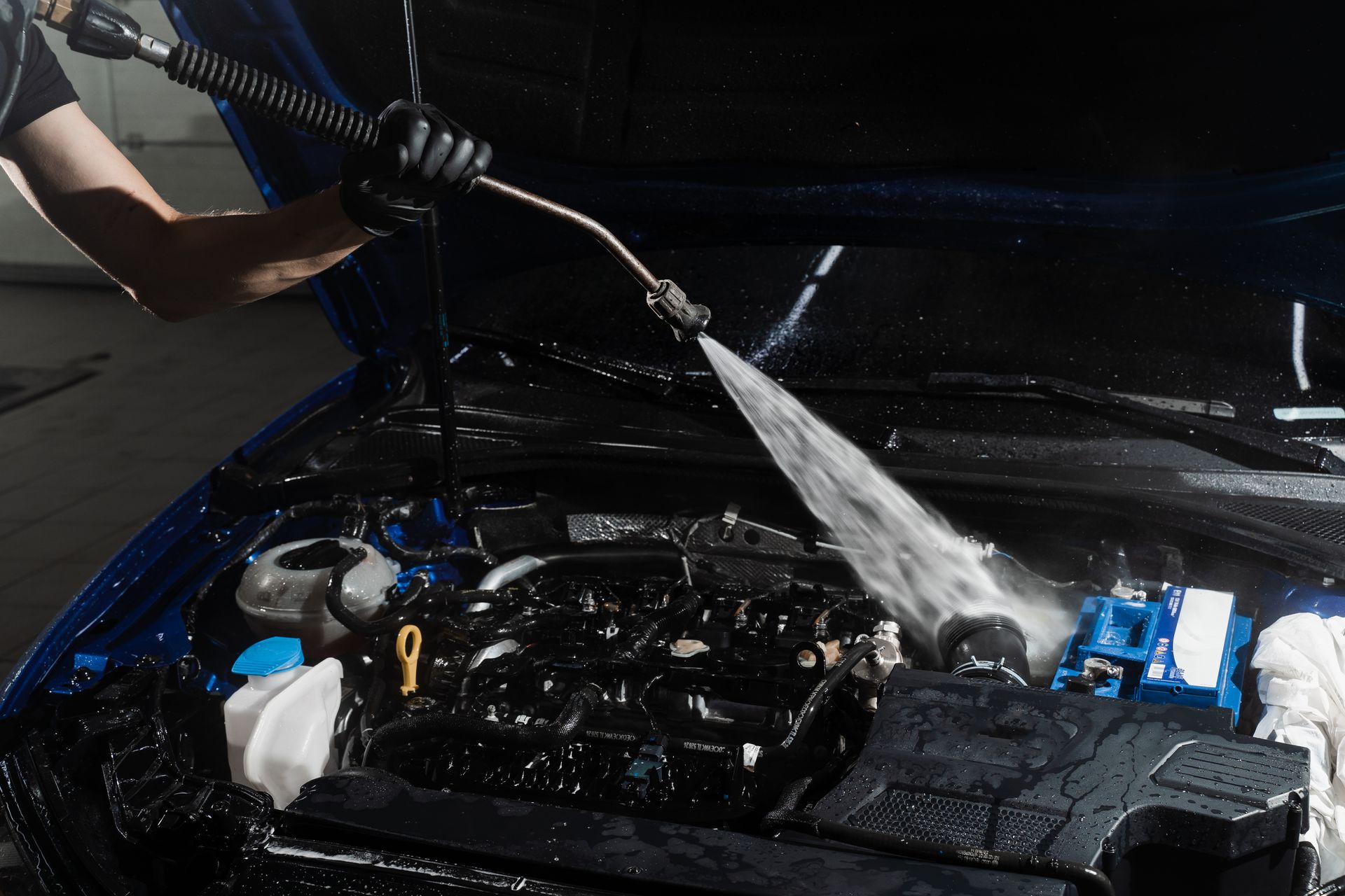 A man is cleaning the hood of a car with a cloth.